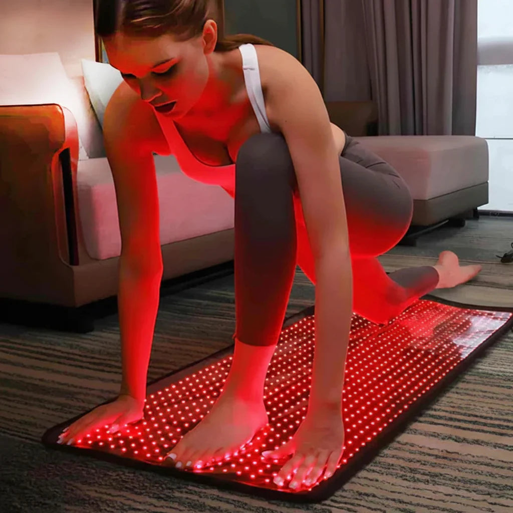 Woman using red light therapy mat for pain relief at home, exercise wellness product