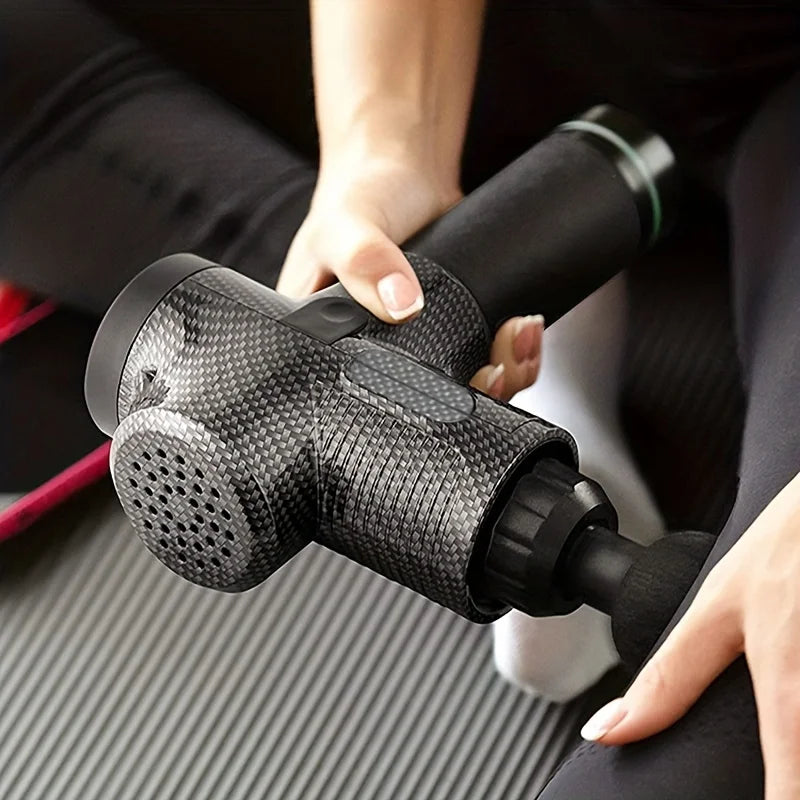 Hand holding carbon fiber massage gun for muscle relief on exercise mat